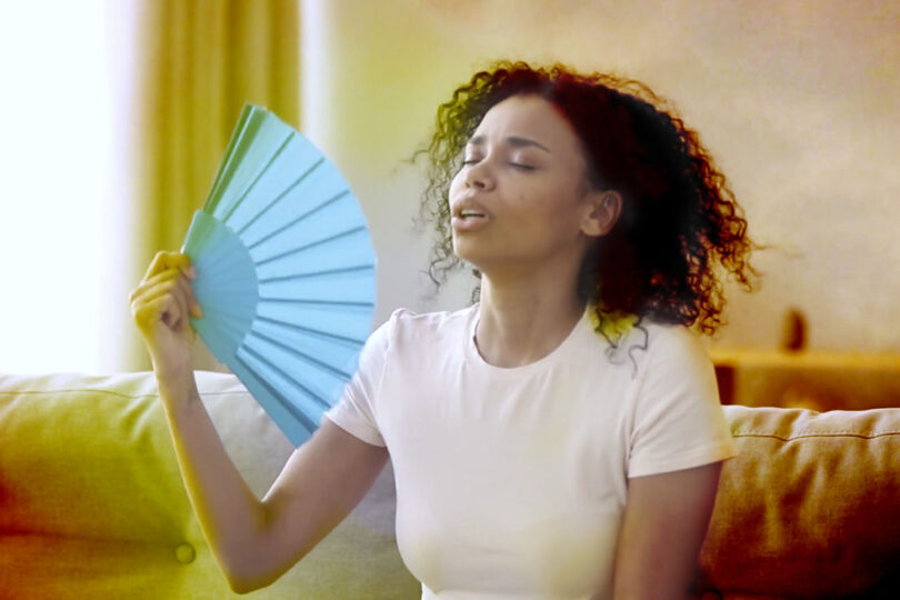 Woman fanning herself in a hot room